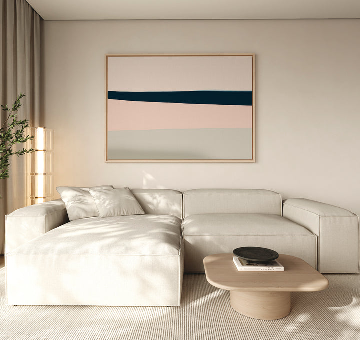 A modern living room features a cream sectional, light wood coffee table with a black bowl, beige curtains, tall plant, and minimalist decor highlighted by the Coastal Blend Canvas Art – Horizontal above the sofa.