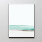 Coastal Breeze Abstract Canvas Art features a minimalist seascape with soft turquoise water, sandy accents, and a white sky in a sleek black frame—perfect coastal wall art for a light gray wall.