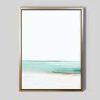 Coastal Breeze Abstract Canvas Art features minimalist gold-framed wall art with soft brushstrokes of a turquoise sea and white sand under a pale sky, adding serene modern elegance to any living room decor.