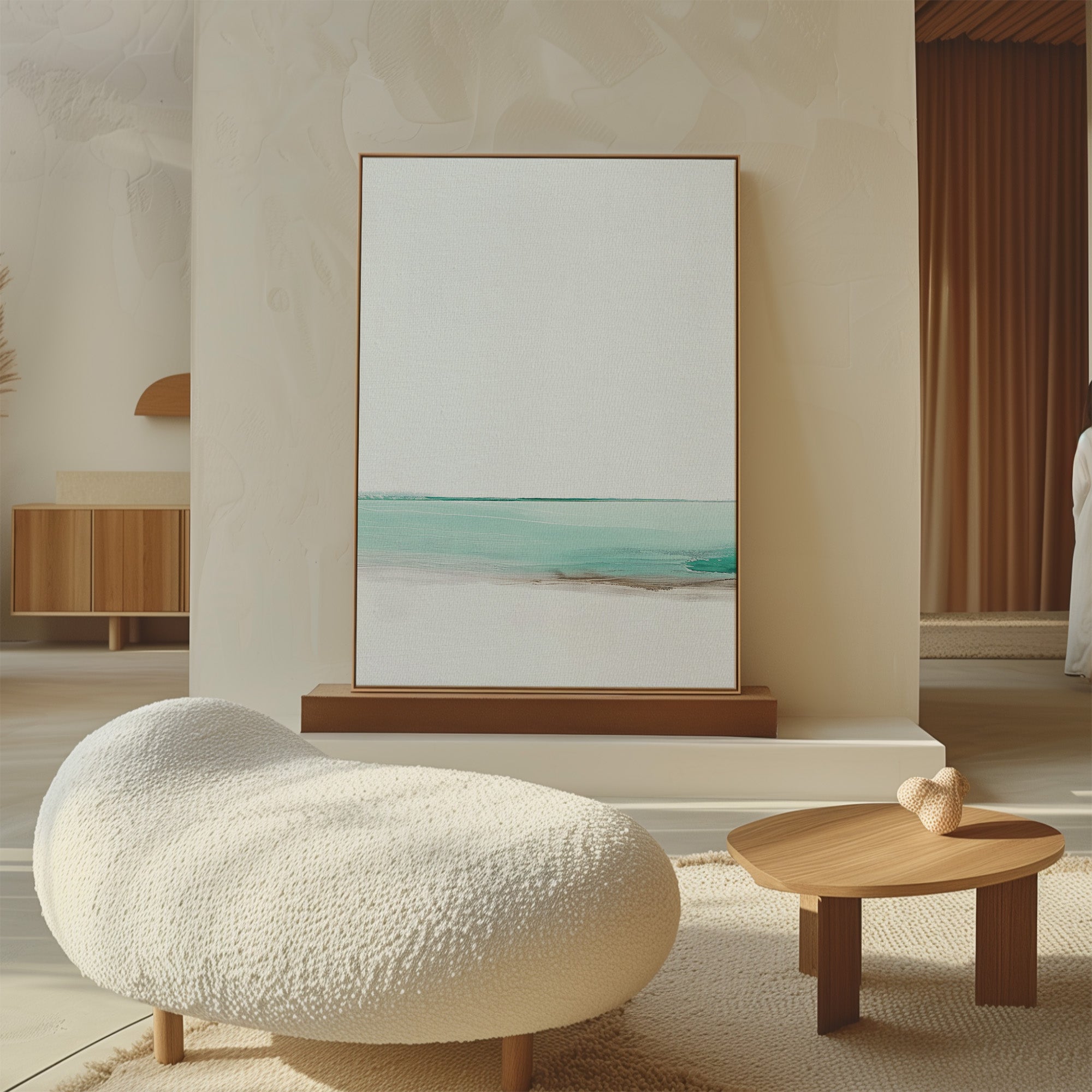 Minimalist living room with a textured white lounge chair, small wooden coffee table with a decorative heart, and the Coastal Breeze Abstract Canvas Art in soft blue and beige tones leaning against the wall.