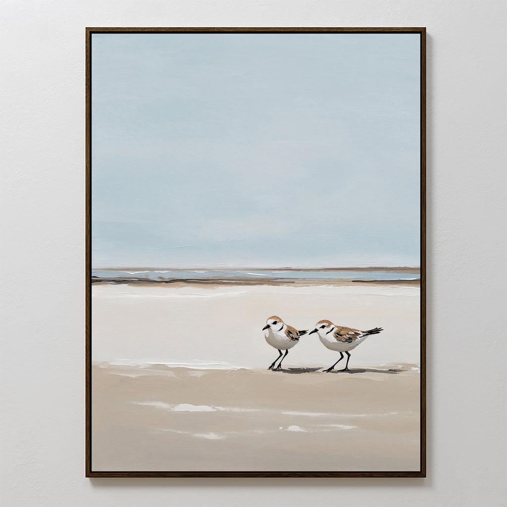 Coastal Chase Canvas Art features two small shorebirds strolling on a sandy beach with sea and sky beyond; soft, neutral tones create a calm, minimalist look—an ideal wall art print for a peaceful space.