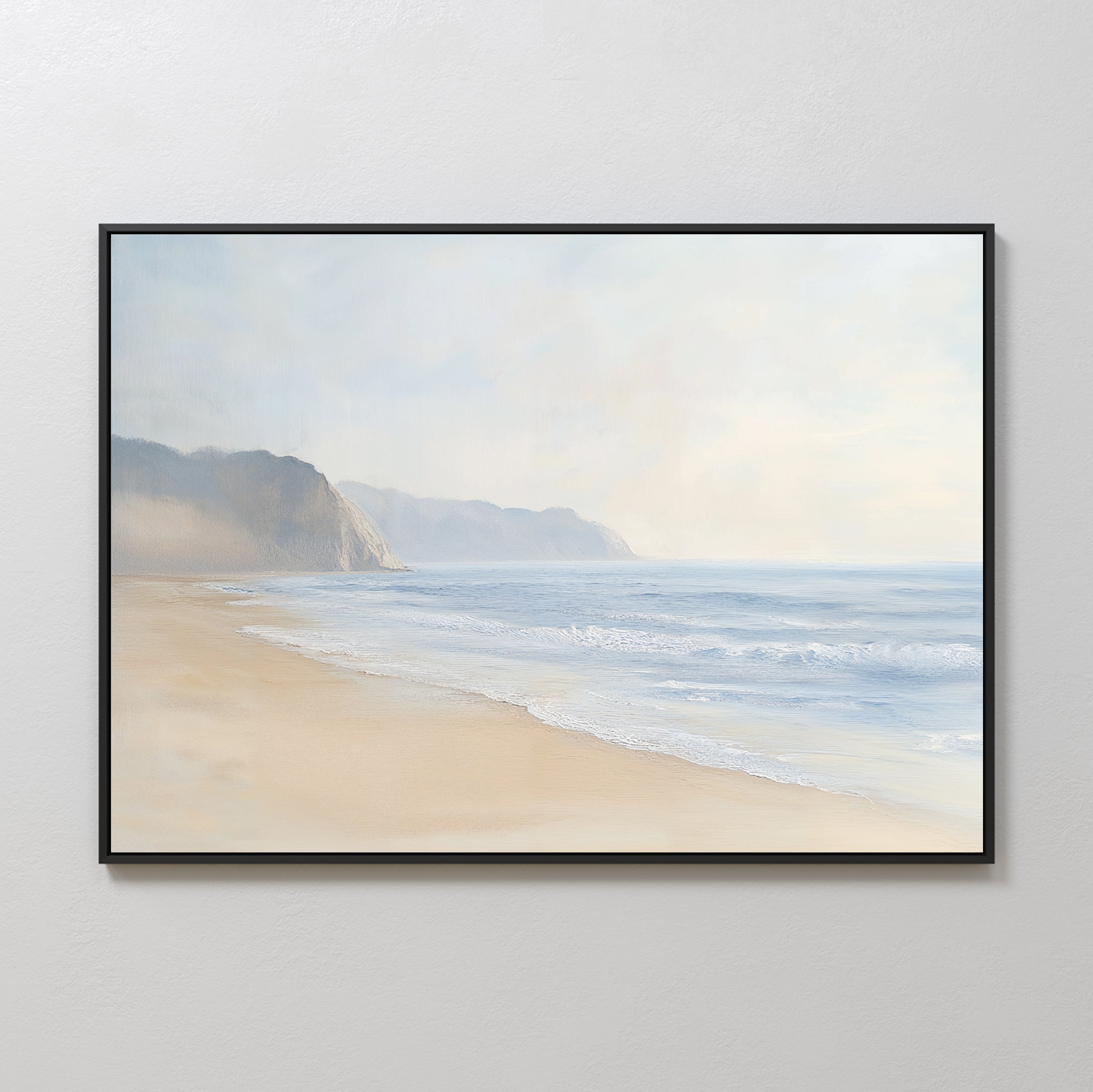 The Coastal Cliffs Canvas Art, featuring gentle waves, sandy shore, and hazy cliffs beneath a cloudy sky, adds serene coastal style to modern home decor when displayed on a plain white wall.