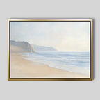 Coastal Cliffs Canvas Art features a serene beach with gentle waves and distant cliffs under a misty sky, framed in gold and black—an ideal tranquil accent for modern decor on pale gray walls.