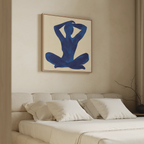 A minimal bedroom features a beige upholstered bed with white pillows and the Cobalt Figure Canvas Art above the headboard. A bare branch in a vase sits on the nightstand.