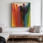 A modern living room displays the Color Cascade Abstract Canvas Art, featuring bold red, blue, yellow, purple, and black brushstrokes. A wooden bench with light cushions complements the neutral, minimalist decor.