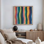 A modern living room with a beige sofa, neutral pillows, a wooden sideboard with decorative vases, and the Color Flow Canvas Art featuring colorful vertical wavy stripes on a white wall.