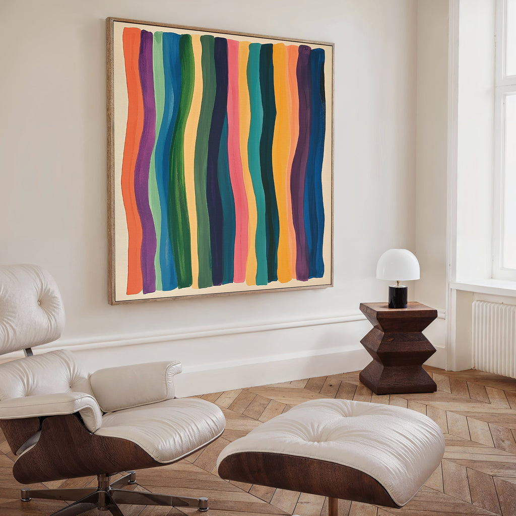 A modern living room features a cream lounge chair and ottoman, a geometric wood side table with dome lamp, and the Color Flow Canvas Art—a bold painting of colorful, wavy vertical stripes—as striking wall decor.