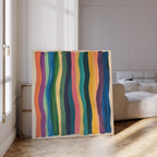 The Color Flow Canvas Art, featuring vibrant vertical wavy stripes, rests against a white wall in a modern living room with parquet floors and a white sofa—perfect for enhancing your living room decor.