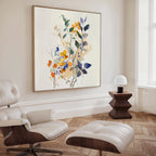 A modern living space features a white leather lounge chair and ottoman, a dark wood side table with a small white lamp, and striking Colorful Branches Canvas Art. Natural light streams in through a tall window.