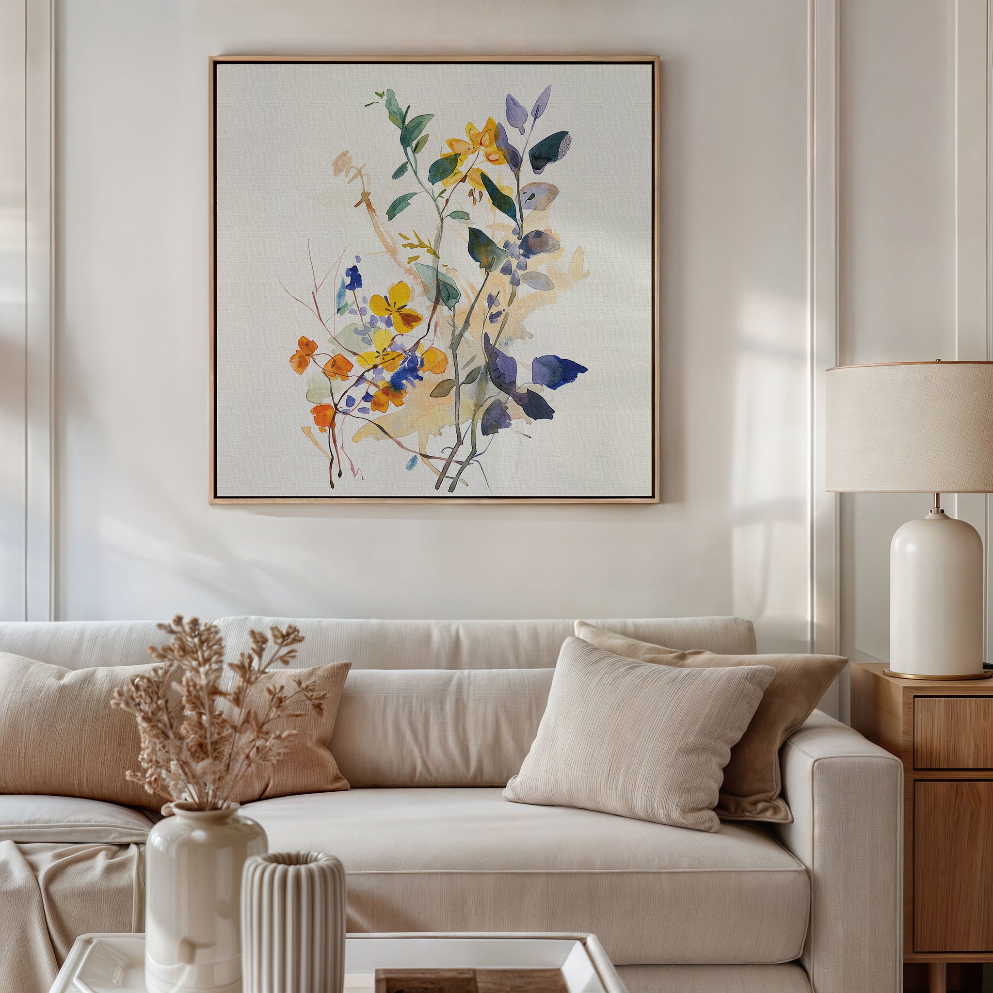 A bright living room with a white sofa, beige cushions, a wooden side table with a lamp, dried flowers in vases, and the Colorful Branches Canvas Art featuring vibrant floral designs hanging above the sofa—ideal for chic living room decor.