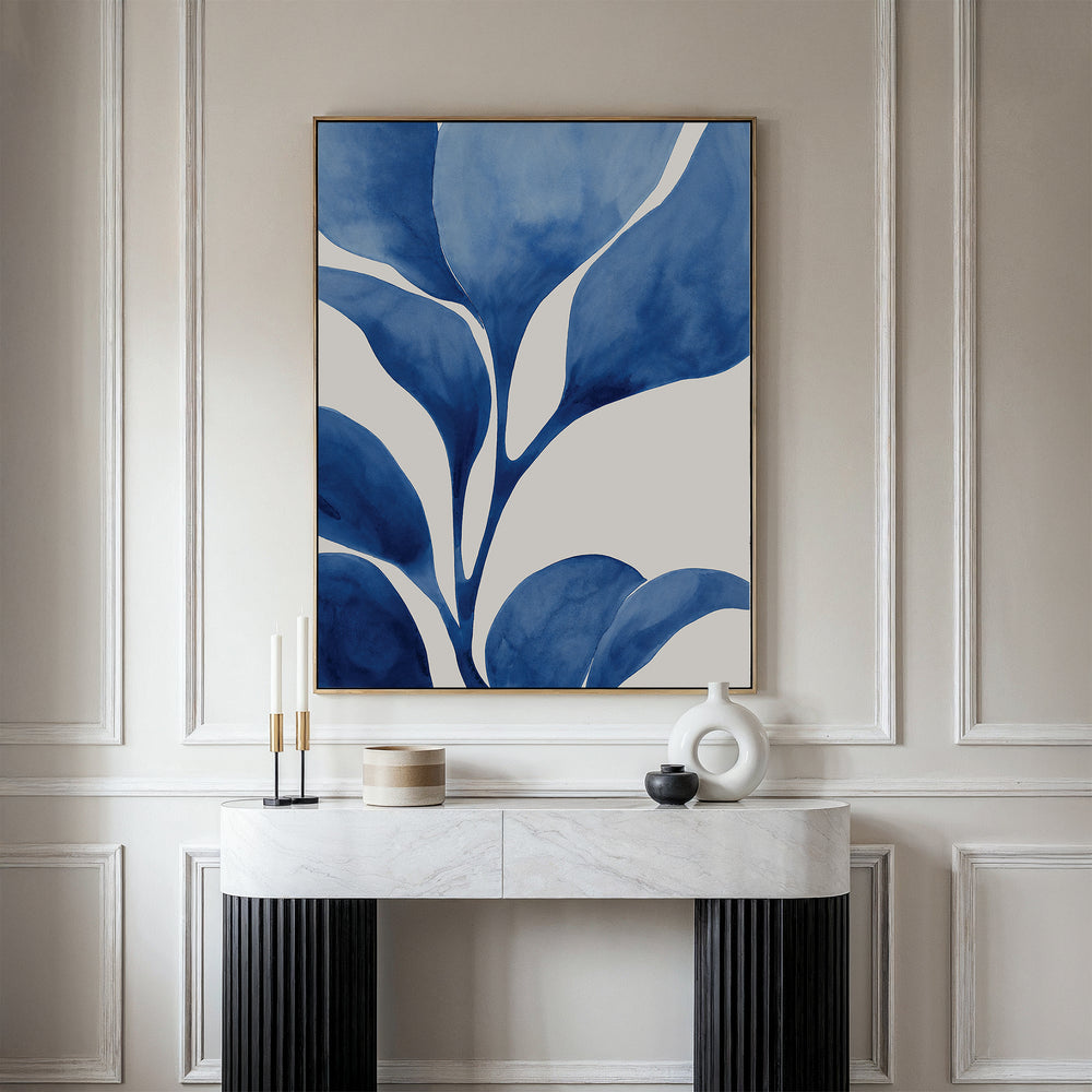 A modern console table with black legs and a white marble top holds candles, a small jar, and a white vase. Above it hangs Cool Tangle Canvas Art—a large abstract botanical painting in blue and white on a light wall.