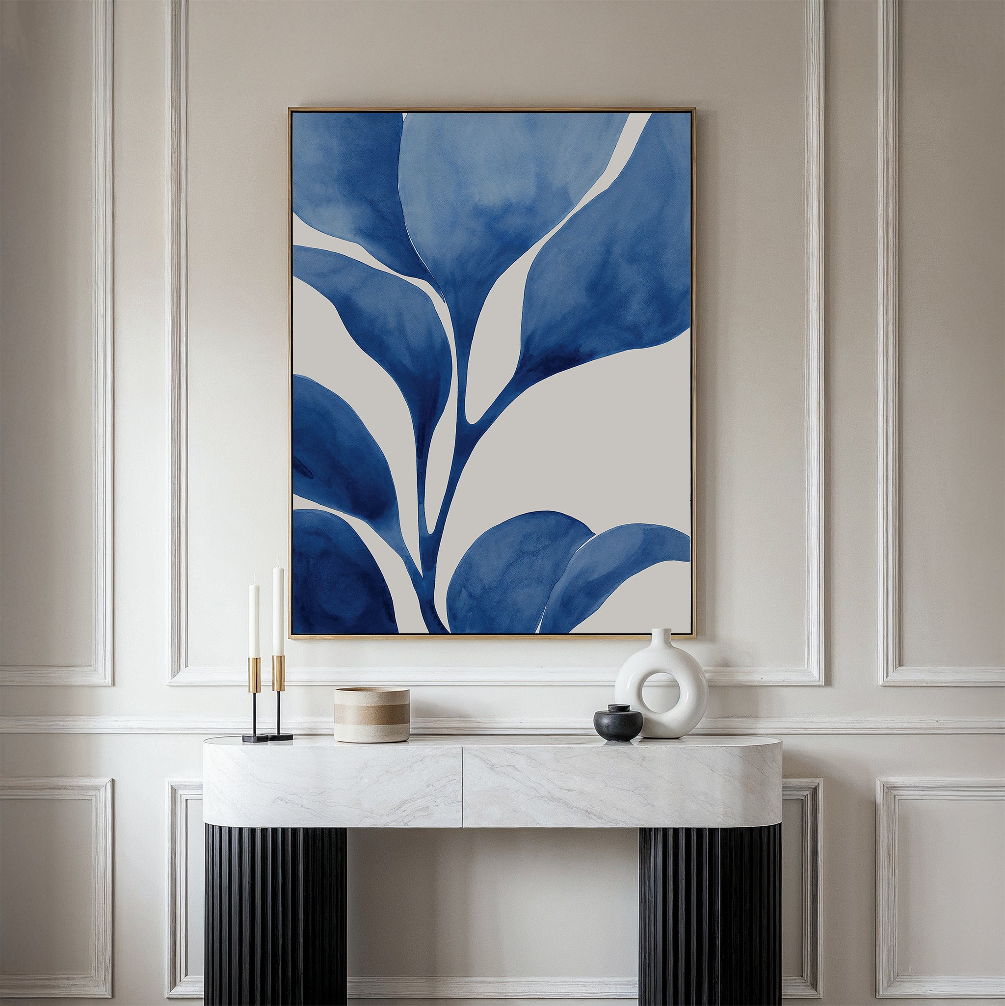 A modern console table with black legs and a white marble top holds candles, a small jar, and a white vase. Above it hangs Cool Tangle Canvas Art—a large abstract botanical painting in blue and white on a light wall.
