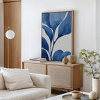 A modern living room with a light wood sideboard, Cool Tangle Canvas Art in blue and white, neutral vases, a small plant, and a white armchair with a cushion. Minimal decor highlights natural tones throughout the space.
