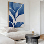 A modern living room featuring a cream sofa with light pillows, a round black coffee table with gold candle holders, and Cool Tangle Canvas Art as blue and white abstract wall art above the sofa.