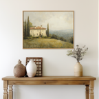 A wooden table with vases and a basket sits against a light wall. Above, the Country Villa Canvas Art depicts an Italian hillside with cypress trees and a cloudy sky—perfect for living room decor.