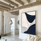 A modern living room with exposed wooden ceiling beams, a beige sofa with white cushions, a tall curved floor lamp, and Curved Lines Abstract Canvas Art on the wall. Natural light flows in from the hallway.