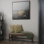 A wooden bench with two light green cushions and a green throw sits beneath the Wildflowers Canvas Art on a white wall, creating a calm, minimalist charm that’s ideal for your living room decor.