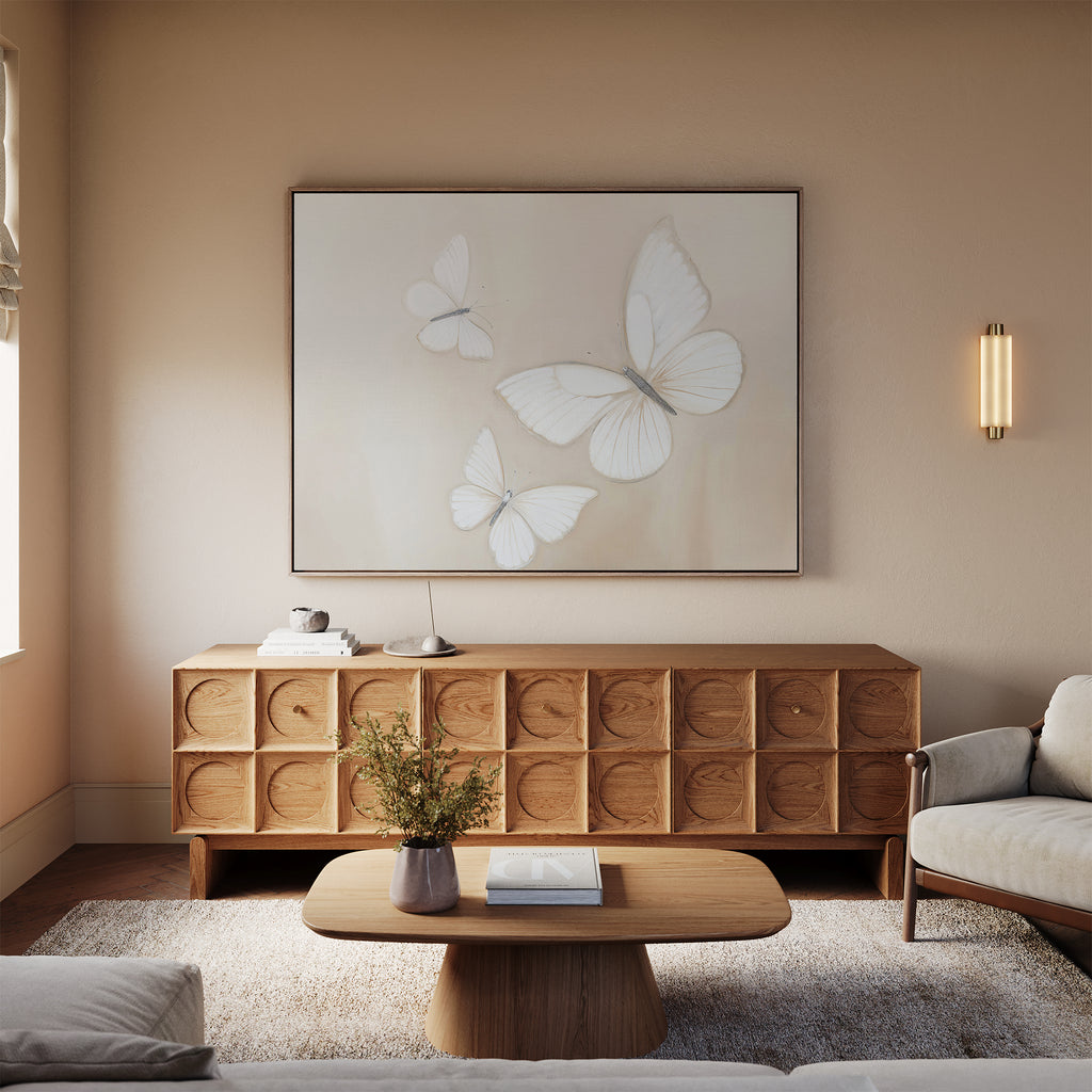 A cozy living room with neutral tones features a Nordic Park wooden coffee table, textured sideboard, white rug, beige sofa, and the Delicate Whites Canvas Art as striking neutral wall decor above the sideboard.