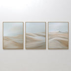 The Desert Serenity Set of 3 features framed abstract paintings with soft, flowing neutral shapes like sand dunes under a pale sky—ideal minimalist wall art for enhancing your modern living room decor.