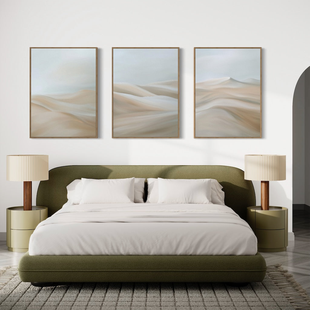 A modern bedroom with an olive green upholstered bed, white bedding, two beige nightstands with matching table lamps, and the Desert Serenity Set of 3 minimalist wall art above the bed.