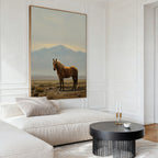 A modern living room with a white sectional sofa, beige cushions, a round black coffee table, and the Desert Watch Canvas Art featuring a chestnut horse and mountain backdrop brings Nordic Park-inspired elegance to the space.