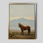 Desert Watch Canvas Art showcases a chestnut horse on rocky terrain with distant mountains and a cloudy sky, framed in a thin gold frame for an elegant touch to any space.