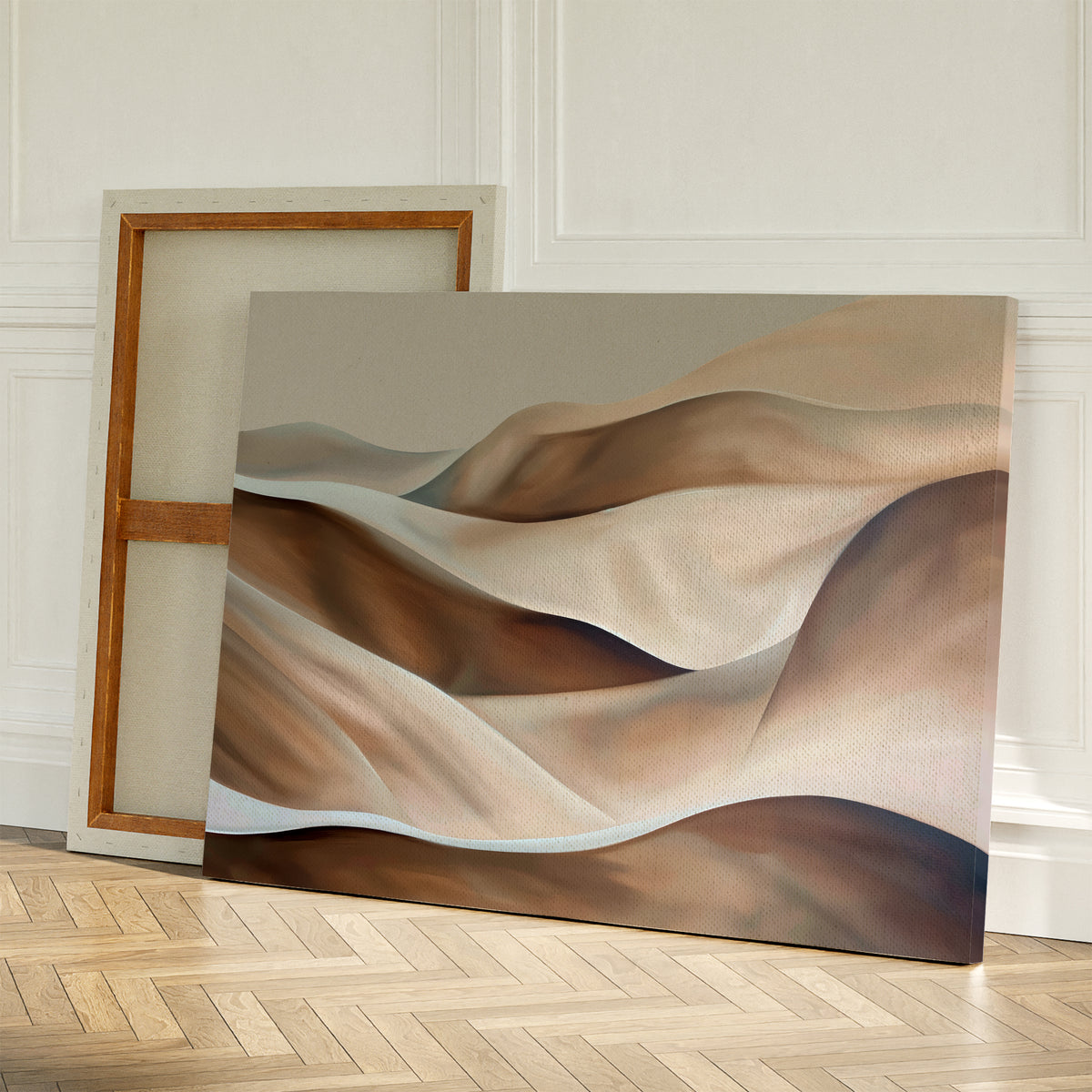 The Desert Waves Abstract Canvas Art, featuring wavy beige and brown shapes, leans against a wall with modern elegance beside a blank canvas showing its wooden frame on a light herringbone wood floor.