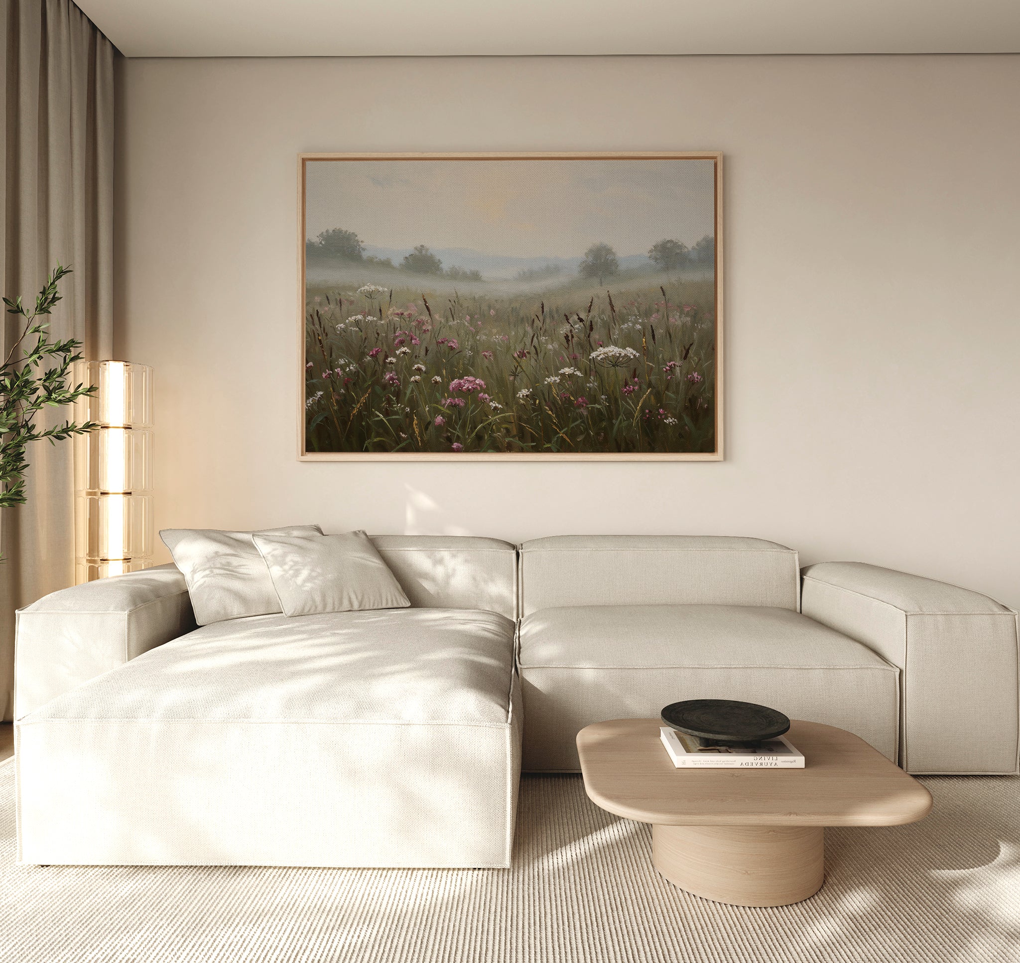 A modern living room with a light beige sectional sofa, wooden coffee table, tall glass lamp, potted plant, and nature-inspired wall art—a large framed Distant Fields Canvas Art—on the wall.