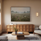 A cozy living room with a light sofa, wooden coffee table, textured wooden sideboard, and nature-inspired Distant Fields Canvas Art hanging above the sideboard. A soft lamp is mounted on the wall.