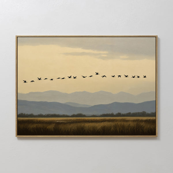 Bring Nordic Park serenity to your space with the Distant Flight Canvas Art, featuring flying birds in a V-formation above grassy fields, distant trees, and layered blue-gray mountains beneath a cloudy sky.