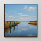 The Dockside Reflection Canvas Art showcases a calm river, tall grass, a wooden dock, and a blue sky with clouds—perfect wall art to add tranquility to any space.