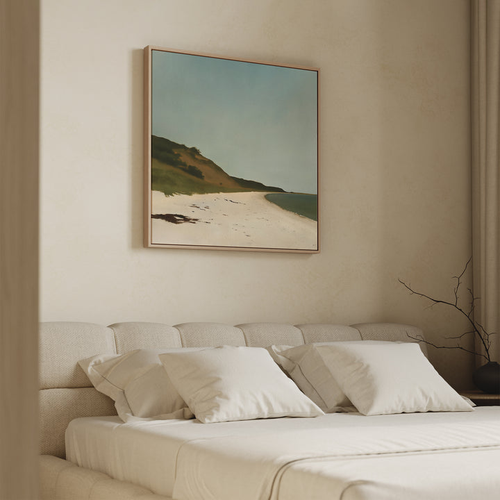 A neutral-toned bedroom features a beige upholstered bed, white bedding and pillows, and the Drift Shore Canvas Art above the headboard. A branch in a vase on the side table adds minimalist charm.