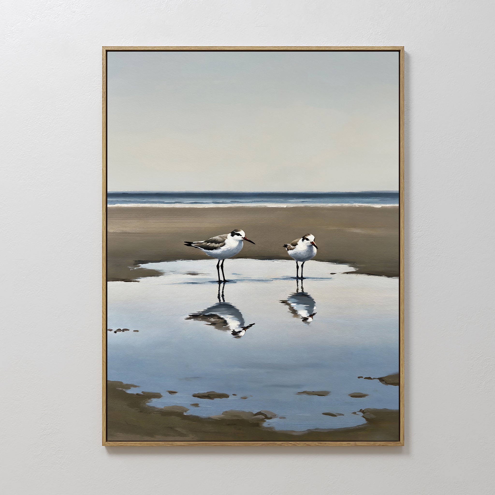 The Drifted Calm Canvas Art features two shorebirds by a reflective pool on a sandy beach with ocean and sky beyond—perfect minimalist wall art to bring a serene coastal vibe to any interior.