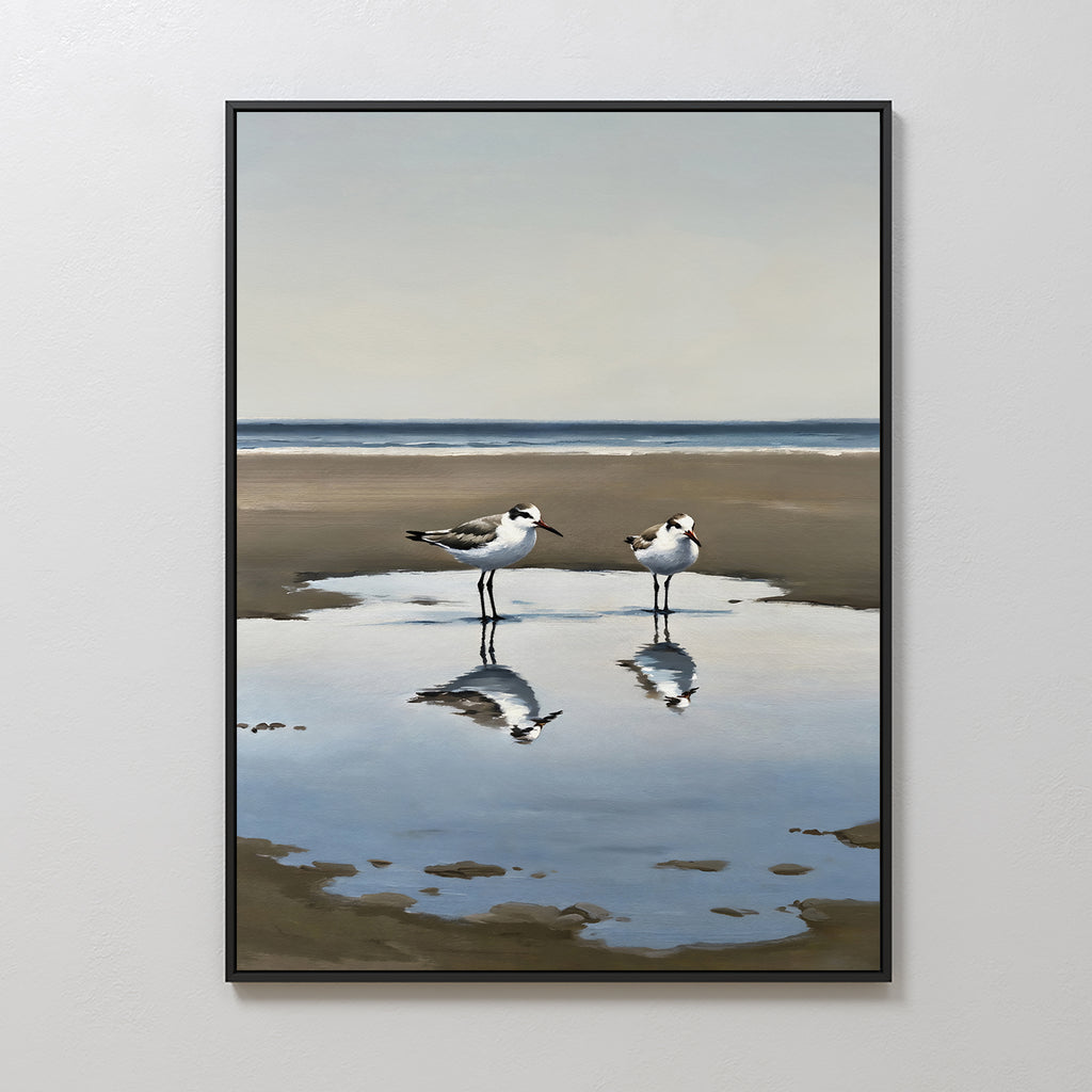 Drifted Calm Canvas Art features a minimalist framed painting of two shorebirds standing in a shallow puddle on a sandy beach, their reflections shimmering—ideal wall art for contemporary interiors and calm coastal spaces.
