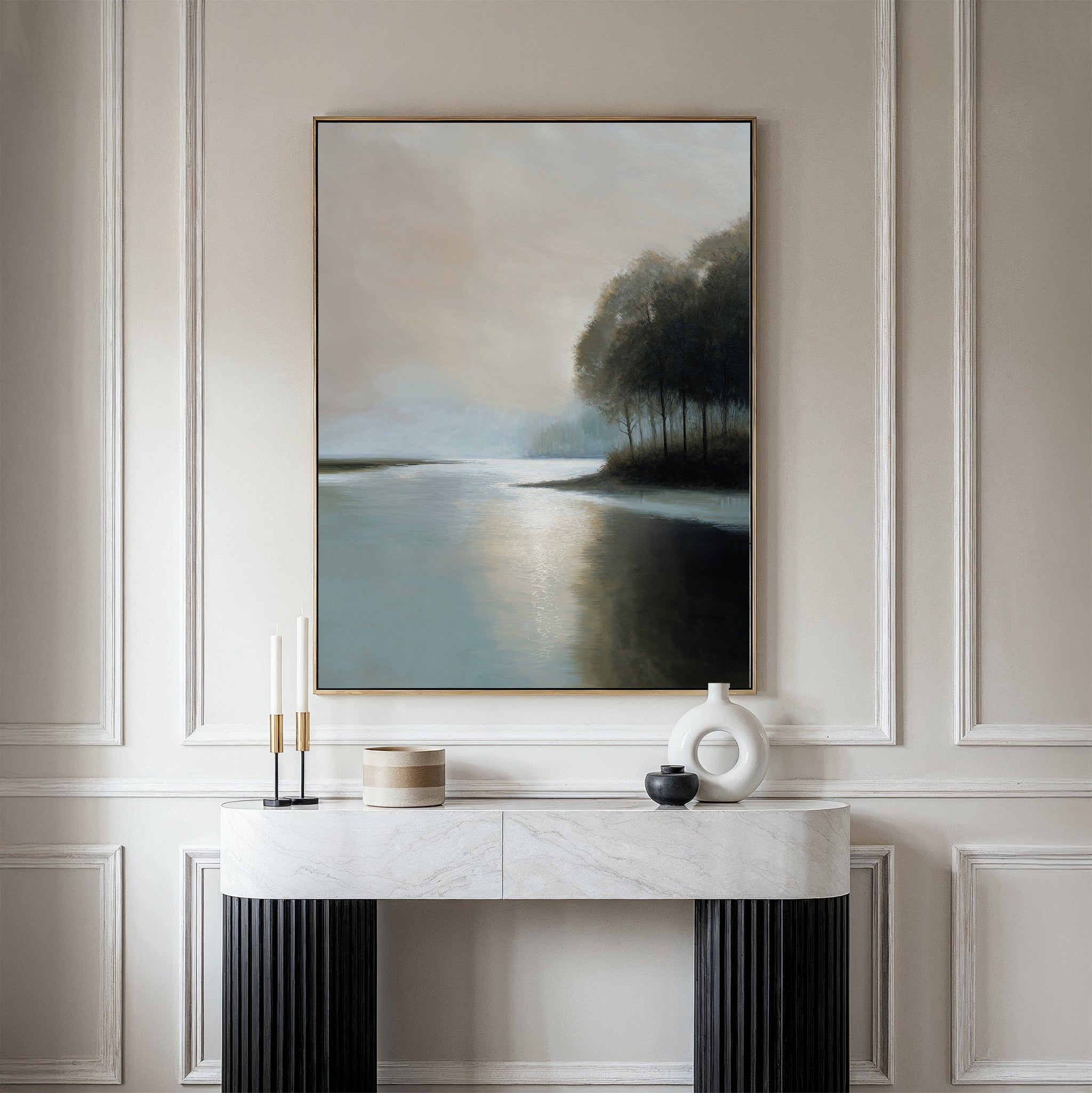 A minimalist console table with decorative objects stands against a paneled wall, above which hangs the Dusklake Canvas Art—a framed painting of a serene lakeside landscape in soft, muted tones.