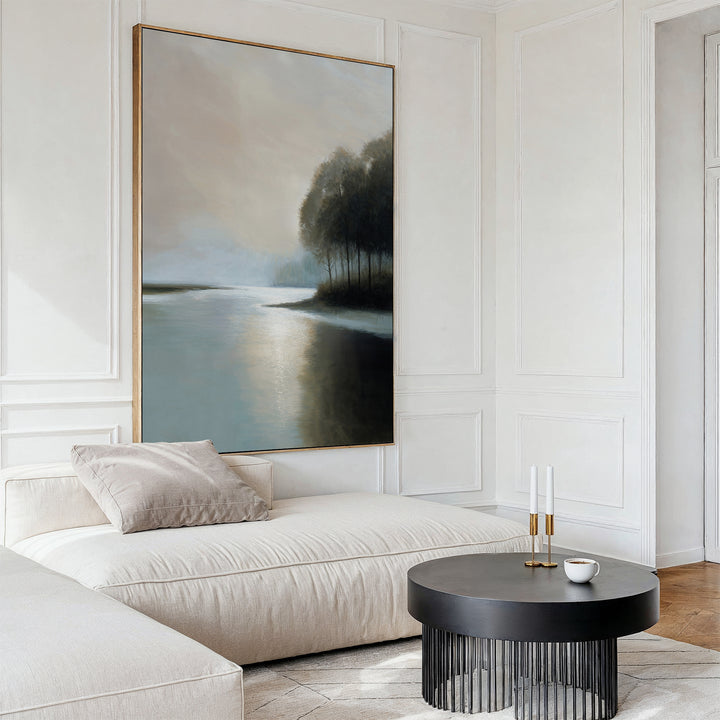 A modern living room features a cream sofa, round black coffee table, two candles, and a cup. Above the sofa hangs Dusklake Canvas Art—a minimalist lakeside landscape—adding calming decor to the space.