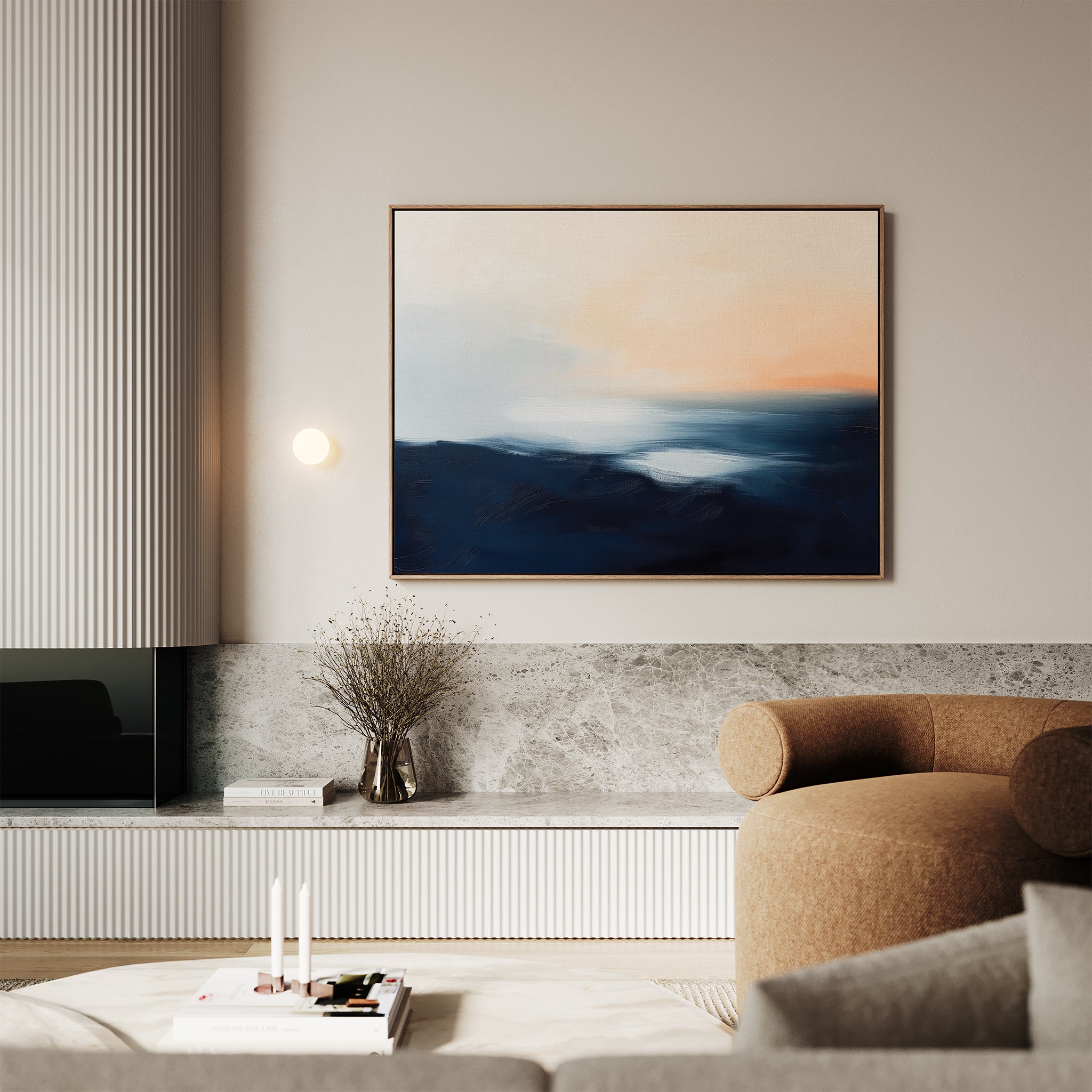 A modern living room with a beige armchair, marble console, and minimalist decor features the Dusk Ridge Canvas Art above the console—an abstract landscape in dark blue and peach resembling a sunrise or sunset over mountains.