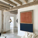 A modern living room with exposed wooden ceiling beams, a curved floor lamp, white walls, the Dusk Stripe Abstract Canvas Art on the wall, and a white sofa in the foreground.