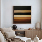 A modern living room with a beige sofa, neutral cushions, wooden sideboard, pottery decor, books, and standout Earth Layers Canvas Art featuring horizontal bands of brown, beige, and black—the perfect Nordic Park-inspired touch.