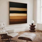A modern living space with a white leather lounge chair and ottoman, a geometric wooden side table with a small lamp, and the Earth Layers Canvas Art featuring horizontal bands of brown, beige, and black on the wall.