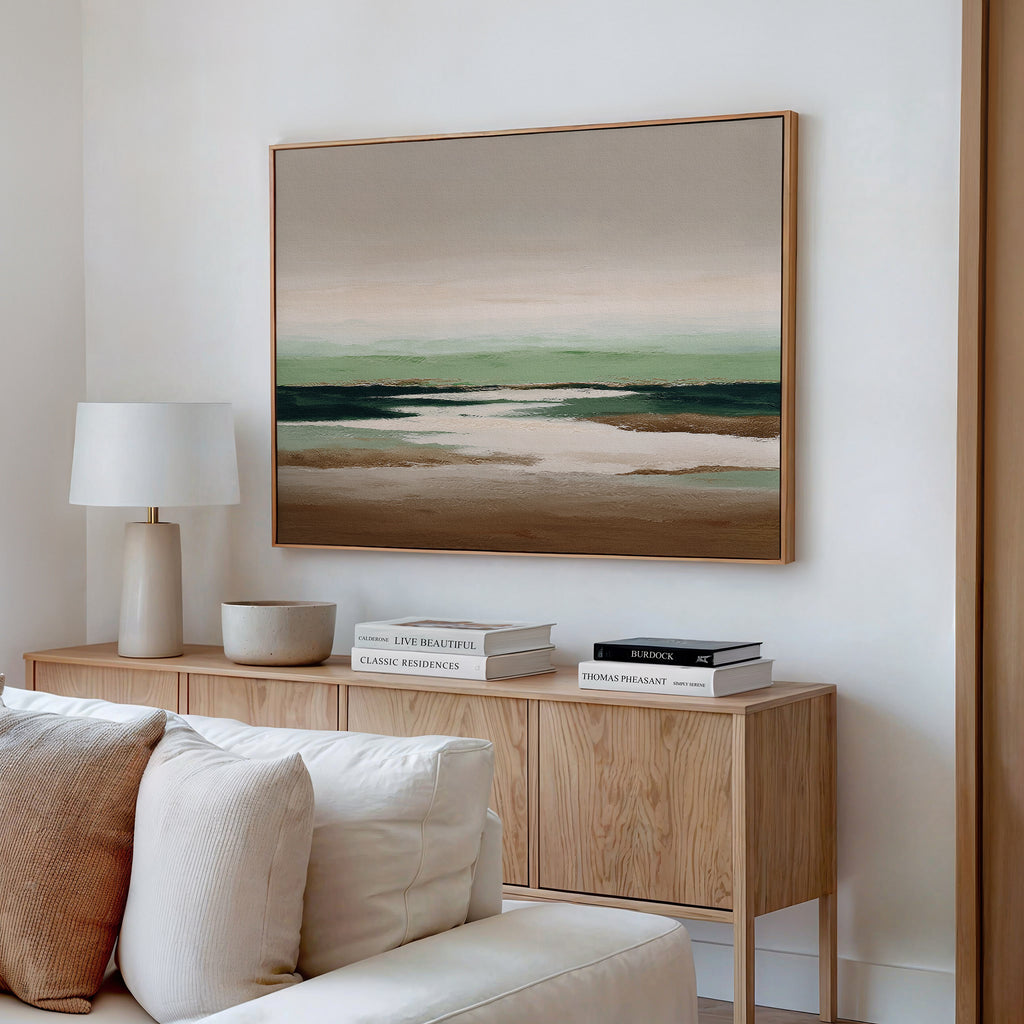 A modern living room with a light wood sideboard, neutral decor, stacked books, a white lamp, and large wall decor—Earthbound Horizon Canvas Art in soft earth tones—hanging above.