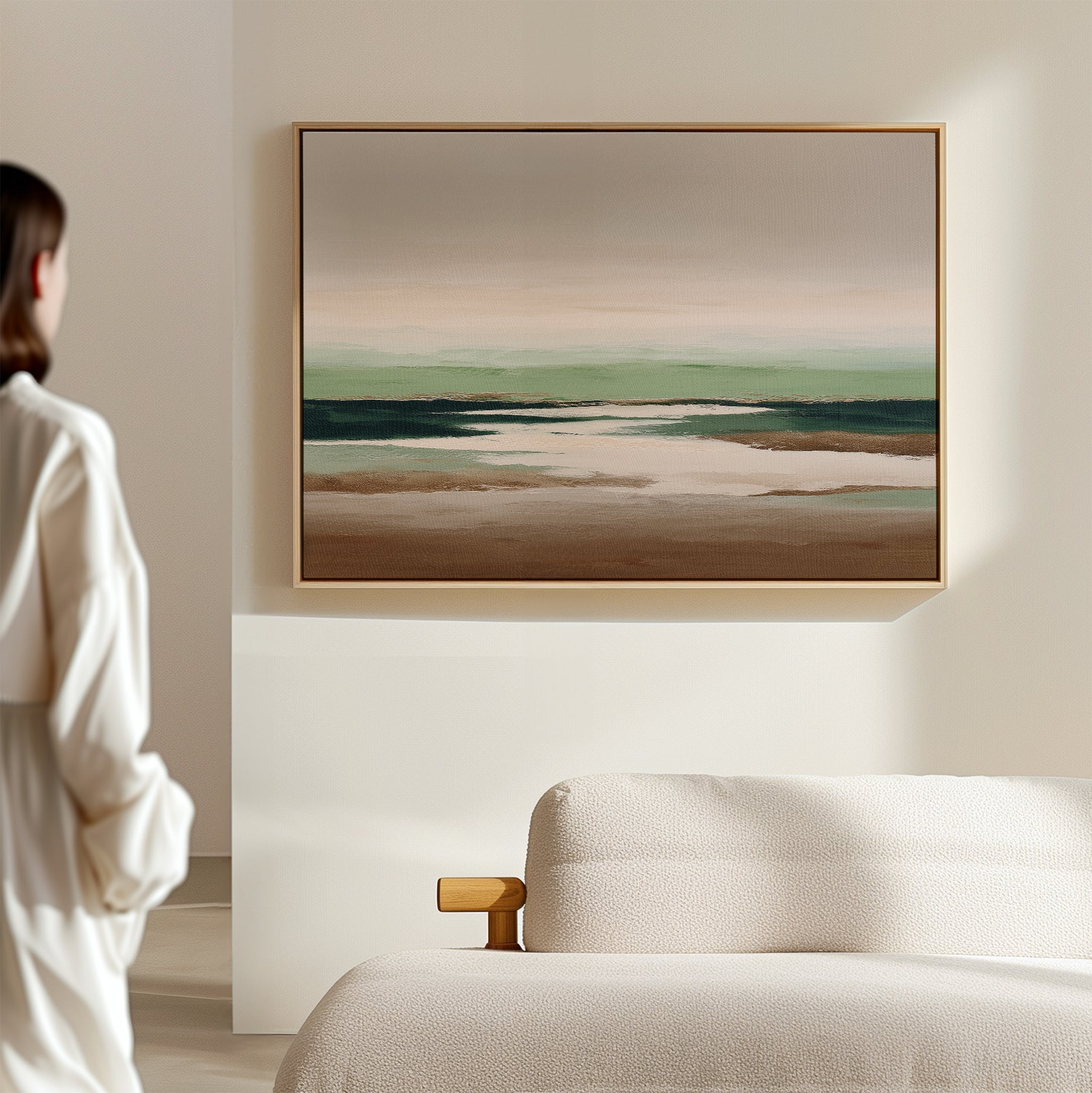 A person stands in a minimalist room, admiring the Earthbound Horizon Canvas Art—a striking abstract landscape with earthy tones and soft greens—displayed above a light-colored textured sofa.