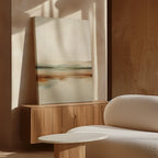 A minimalist living room with a light wood sideboard, the Earthly Hues Abstract Canvas Art leaning against the wall, a white textured sofa, and a round white coffee table, all bathed in natural sunlight.