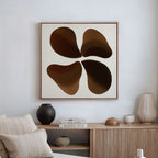 A modern living room with neutral decor features a beige sofa, light wood sideboard, vases, and Earthy Blooms Canvas Art—a minimalist piece with four overlapping brown shapes on a white background.