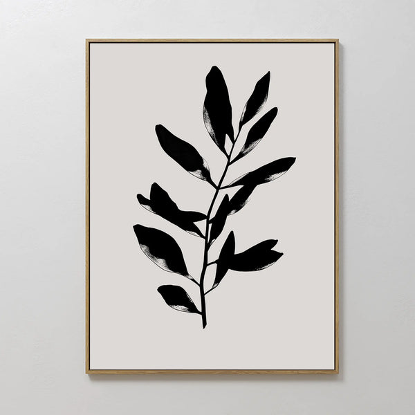 The Ebony Leaf Canvas Art showcases a black leafy branch silhouette on a light beige backdrop, set in a slim gold frame—stylish botanical wall decor ideal for enhancing modern interiors.