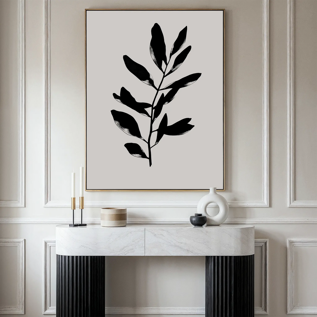 A minimalist living space features the Ebony Leaf Canvas Art above a white marble console table with candles and ceramic vases, creating an elegant focal point for modern interiors against a paneled wall.