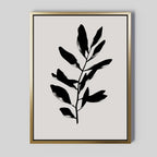 Ebony Leaf Canvas Art: a minimalist print with a black leafy branch silhouette, centered on light beige and framed in thin gold—ideal botanical wall art for modern interiors.