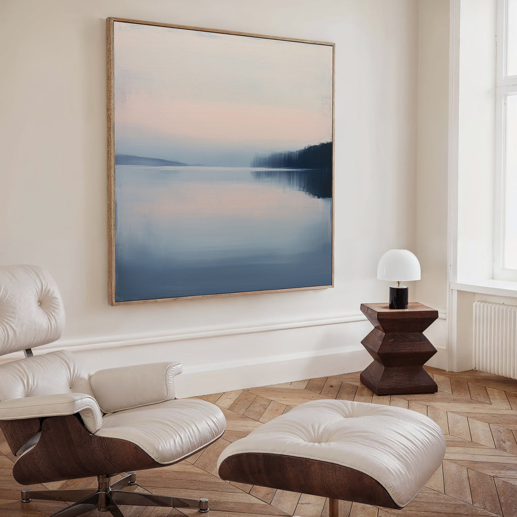 A modern living room with a white leather lounge chair and ottoman, a geometric wooden side table with lamp, and minimalist Echo Lake Canvas Art framed on the wall.