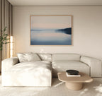 A modern living room with a light beige sectional, a low wooden coffee table featuring a black bowl, floor lamp, potted plant, and the Echo Lake Canvas Art – Horizontal on the wall adds tranquility to the space.