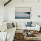 A cozy living room with white shiplap walls, a spacious white sectional topped with assorted pillows, a wooden coffee table decorated with accents, and the calming Echo Lake Canvas Art – Horizontal displayed above the sofa.